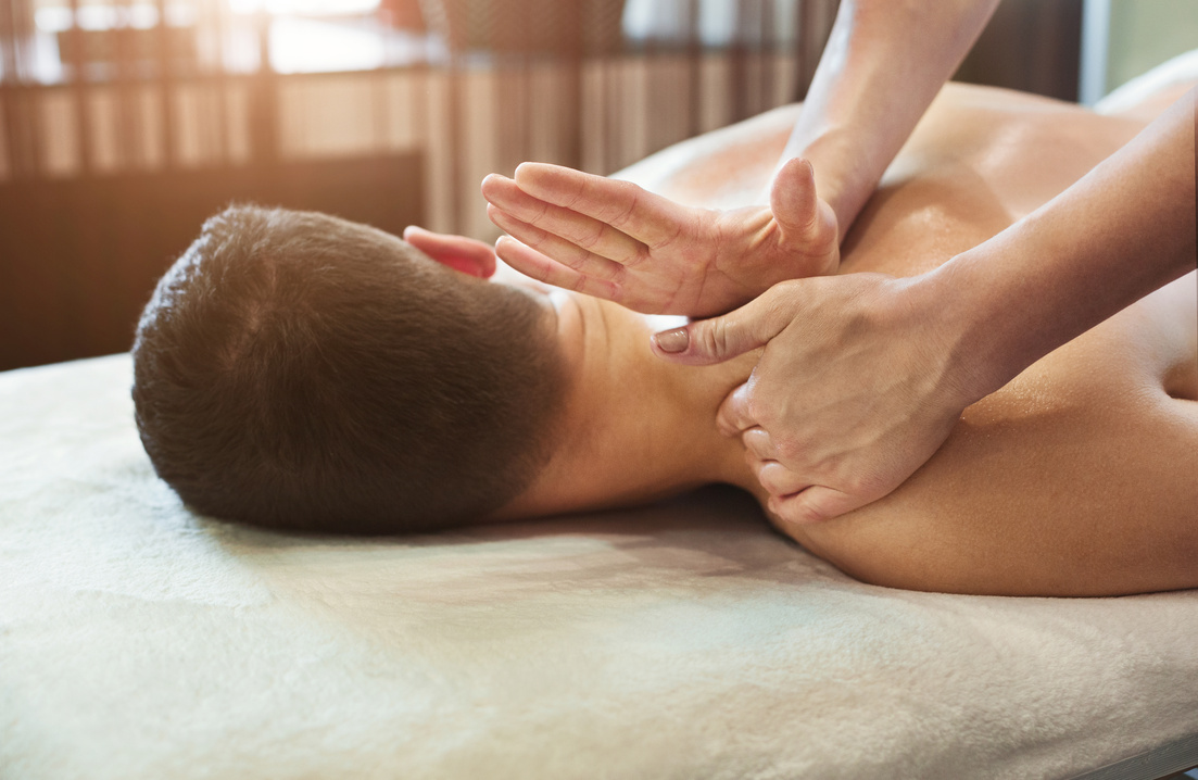 Female massage therapist massaging male shoulders